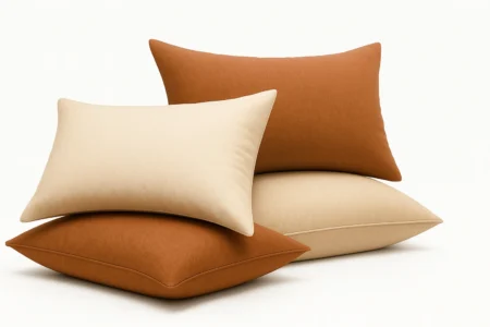 Melhores Travesseiros : Quatro travesseiros empilhados sobre fundo branco — o da base e o de trás em terracota, o do meio em bege e o do topo em terracota, com contornos definidos e textura suave, transmitindo conforto e estilo minimalista.